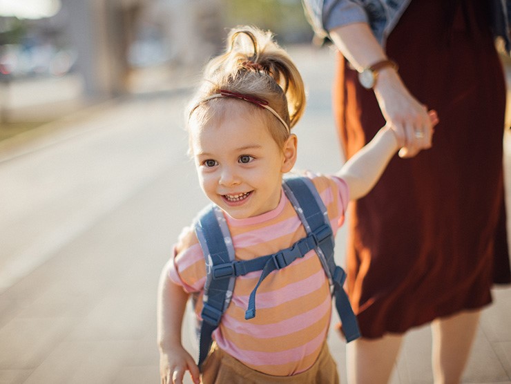 A preschooler smiling and holding her mother's hand