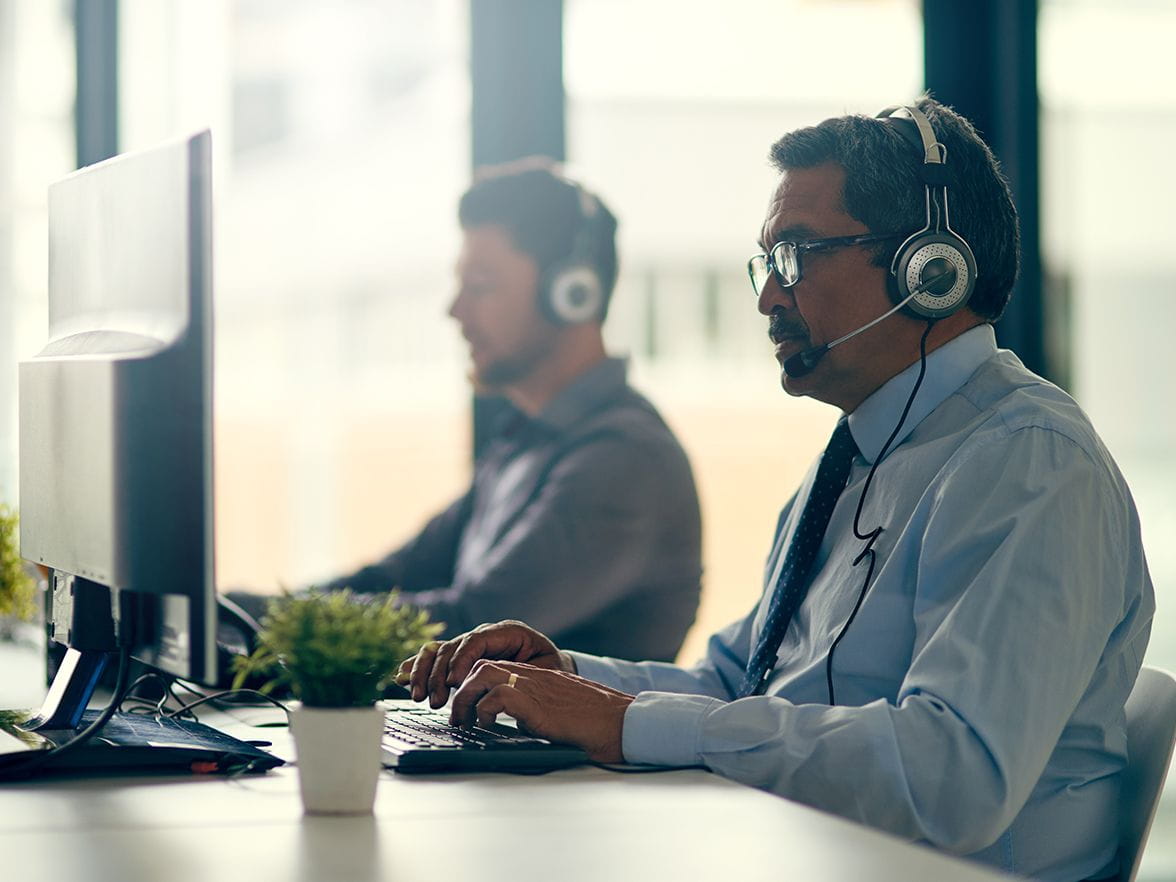 male employee with headset on his computer working