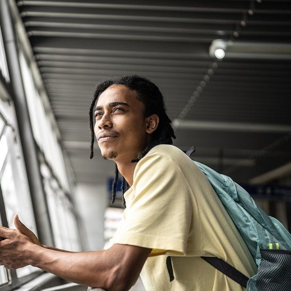 male student wearing backpack looking out window