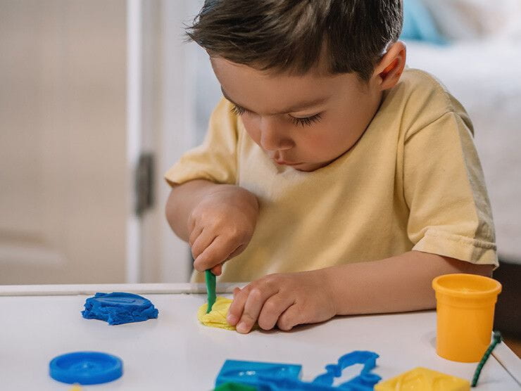 Preschooler working on a play dough project at home