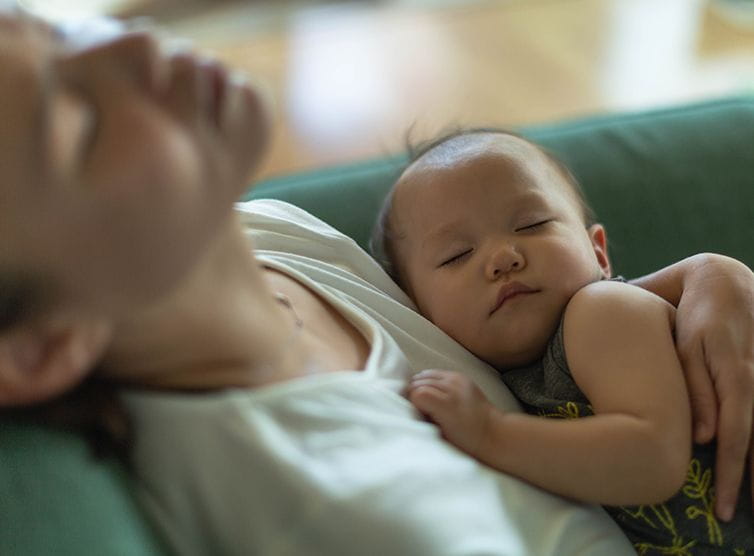 Exhausted mom with her sleeping baby