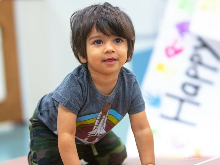 Toddler crawling on the floor and smiling at Bright Horizons day care 