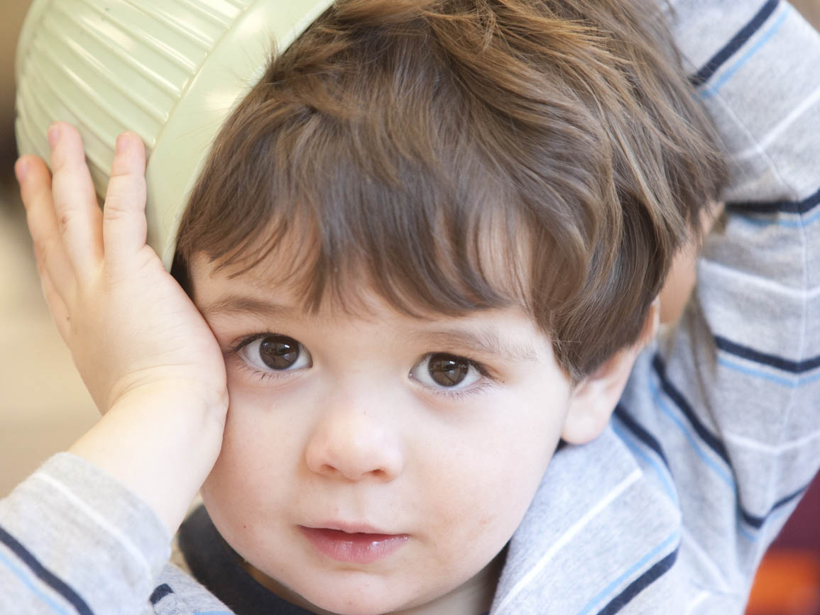 A toddler with a bowl on his head