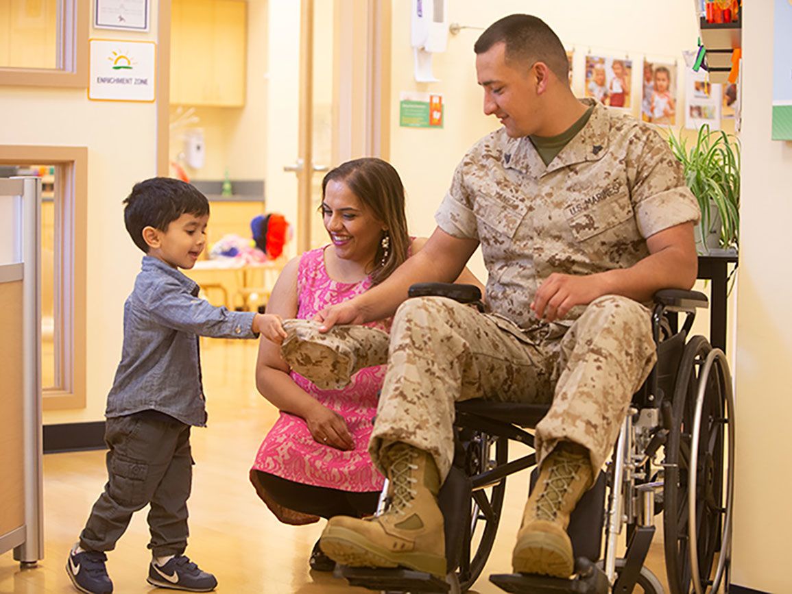 Young boy shaking hands with a wheelchair-bound veteran