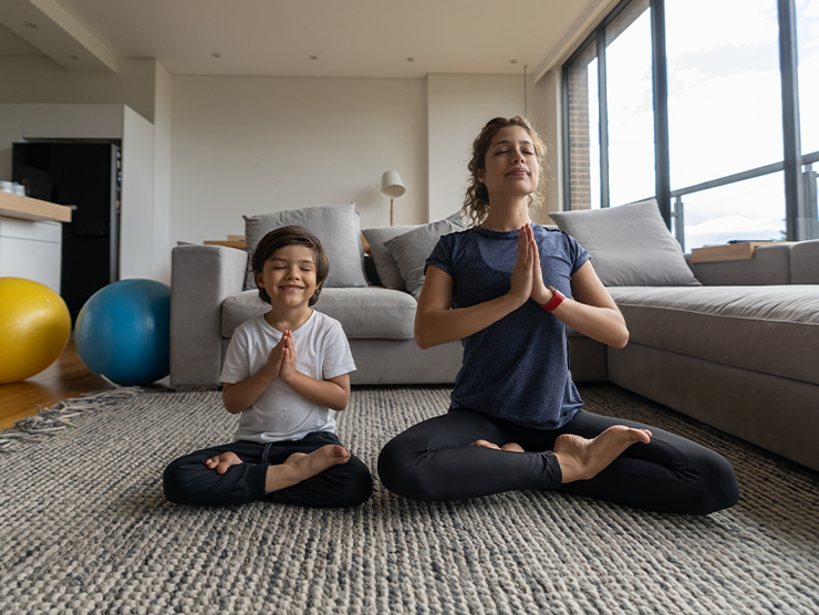 A mon practicing yoga at home with her son.