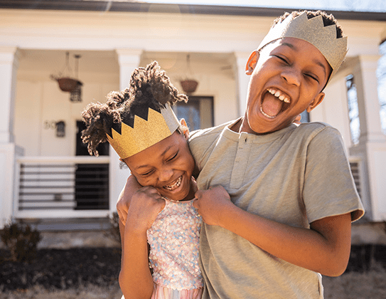 Two children playing in paper crowns