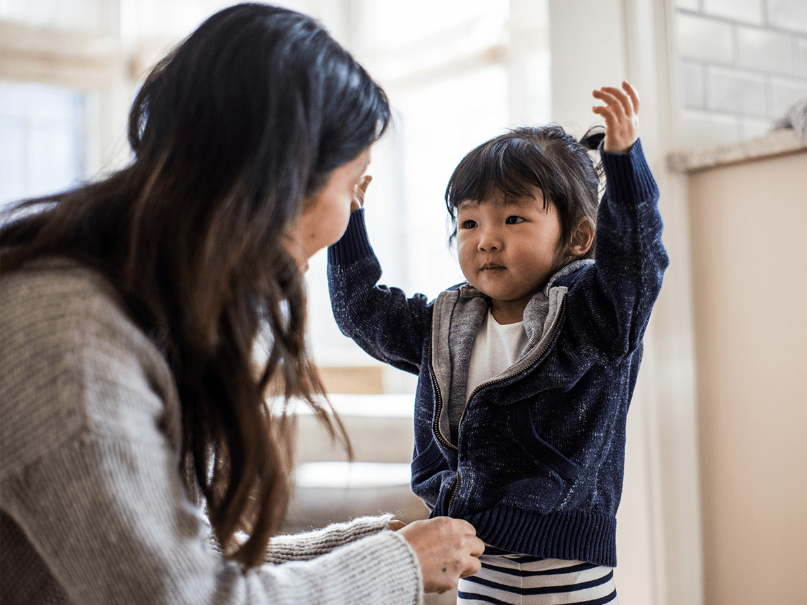 A woman helping a child get ready for the day