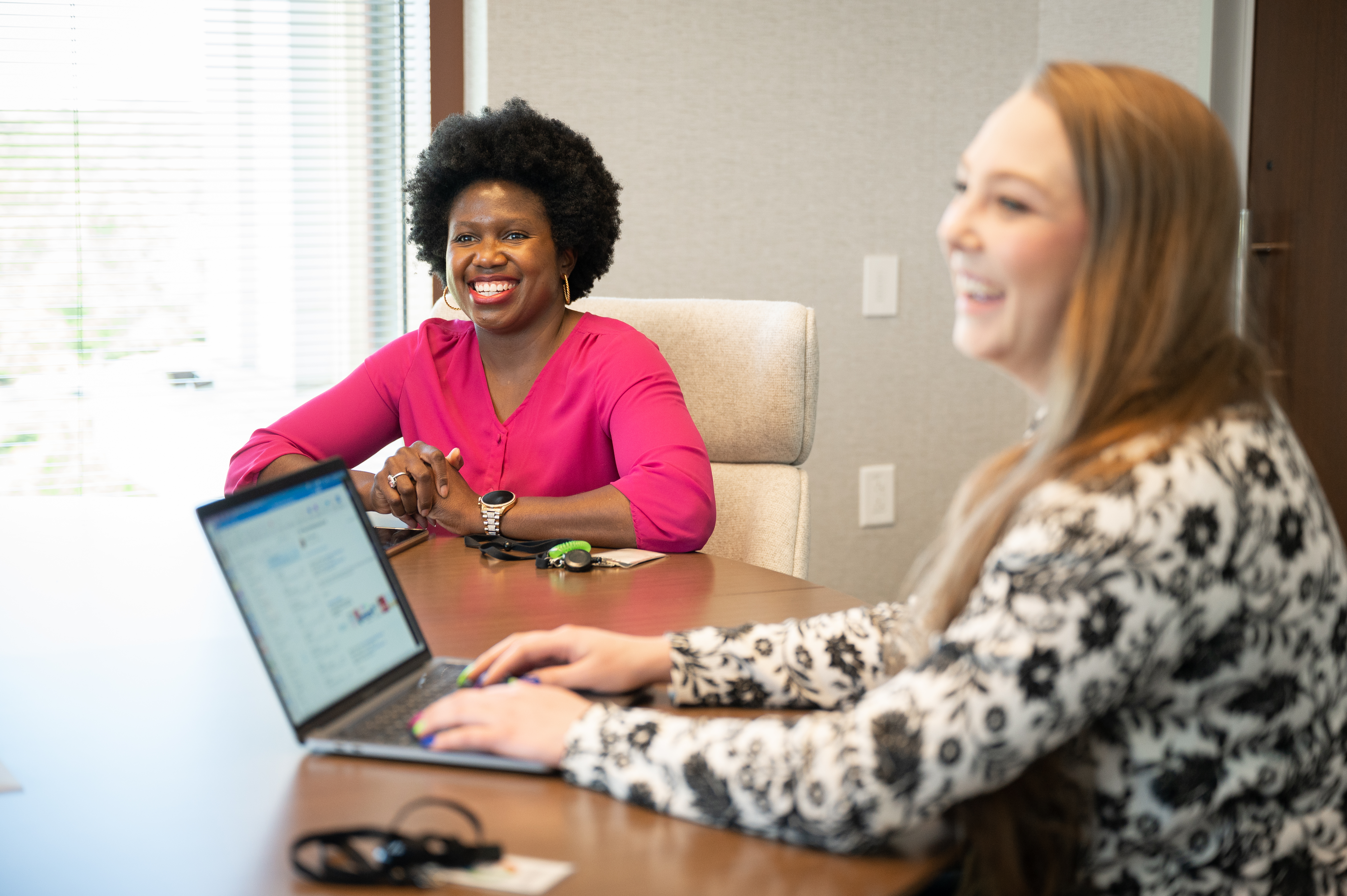 Two female colleagues sitting at a table smiling