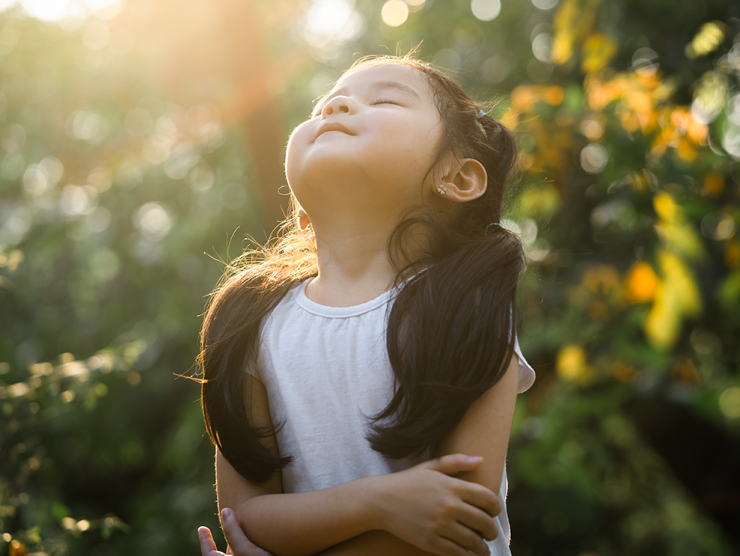 Girl closing her eyes and smiling as the sun shines down on her face