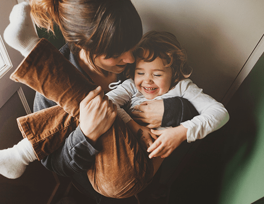 A woman holding a laughing child in her arms