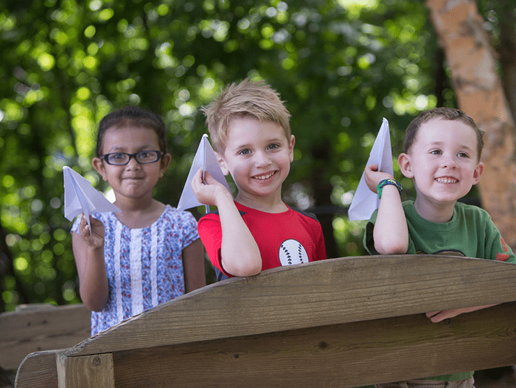 Three children throwing paper airplanes