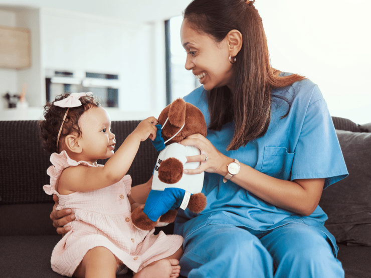 A healthcare professional sitting on her couch with her toddler-aged daughter